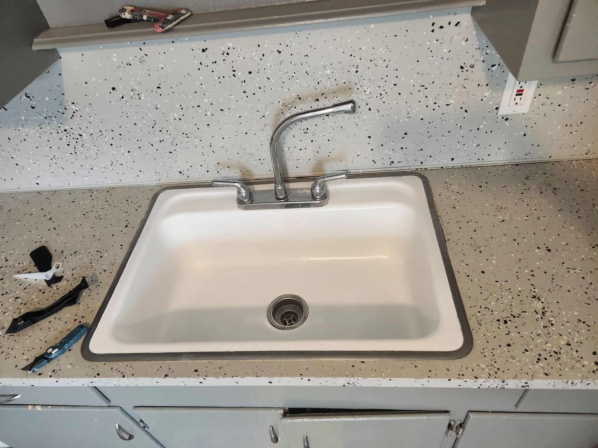 Kitchen sink resurfaced in bright white with speckled countertop finish
