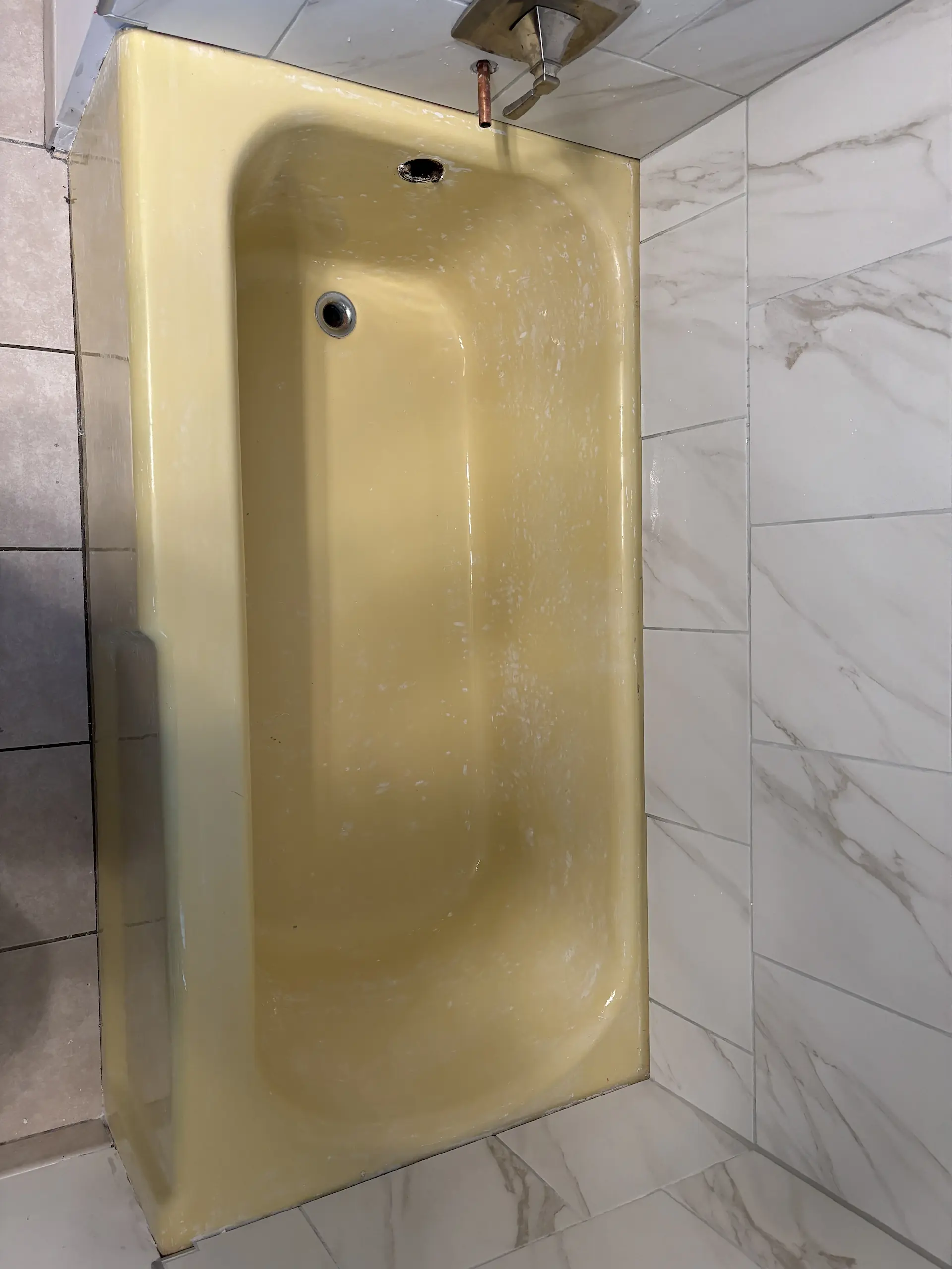 Worn yellow bathtub before refinishing in an Ohio home