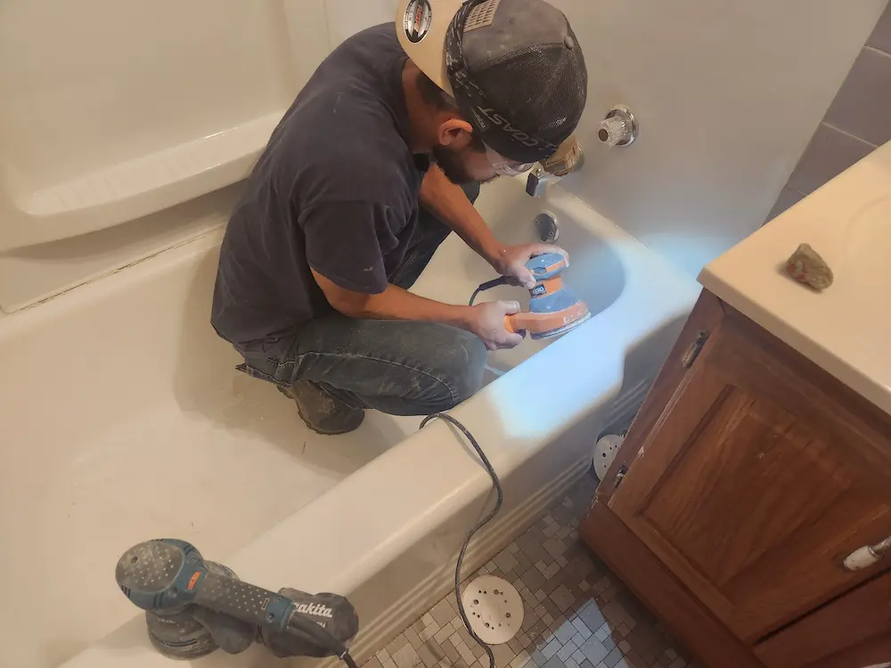 Reglaze Pro technician sanding a bathtub during surface preparation