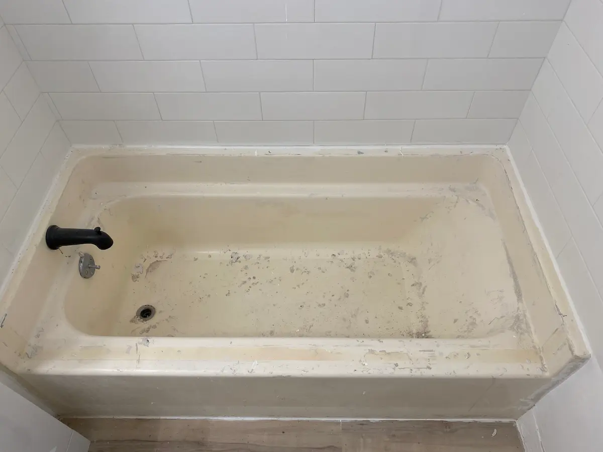 Worn bathtub before refinishing showing wear at the drain