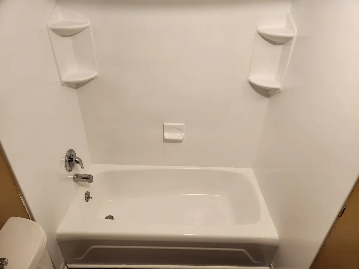 Same bathtub and surround refinished in bright white by Reglaze Pro, shelves and soap dish included