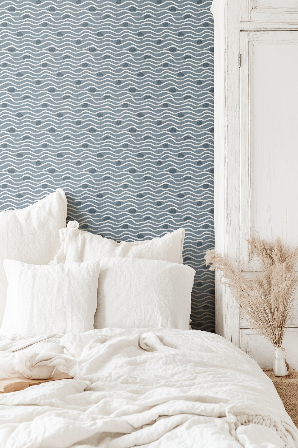 Minimalist blue and white "Water Flow" textured pattern wallpaper with a rhythmic pebble and wave design, creating a calm and restorative atmosphere in a light-filled bedroom.