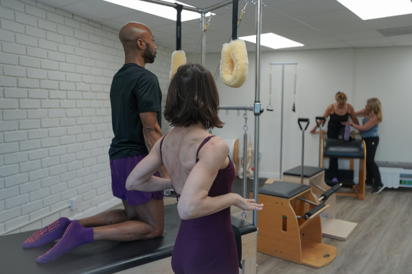 Pilates studio photography of a trapeze tower training session with multiple clients in a Los Angeles wellness studio captured by Roll The Media