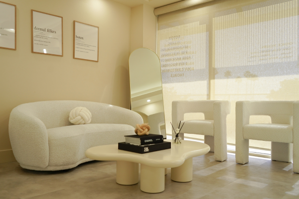 Interior photography of a luxury aesthetic clinic waiting room featuring botox and dermal filler service displays with neutral-toned modern furniture by Roll The Media