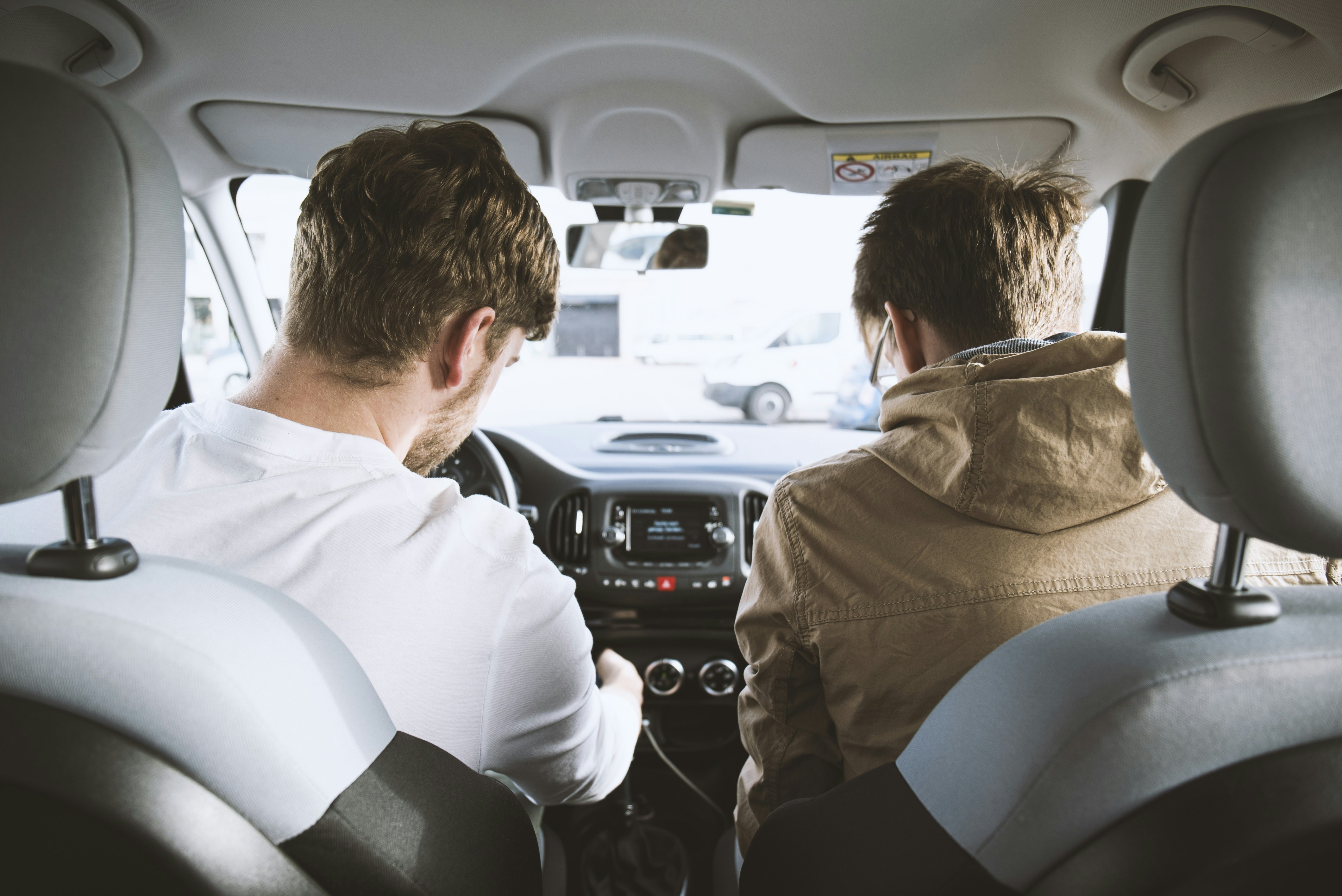 Two teen boys driving to school taken from the back seat of the car. 