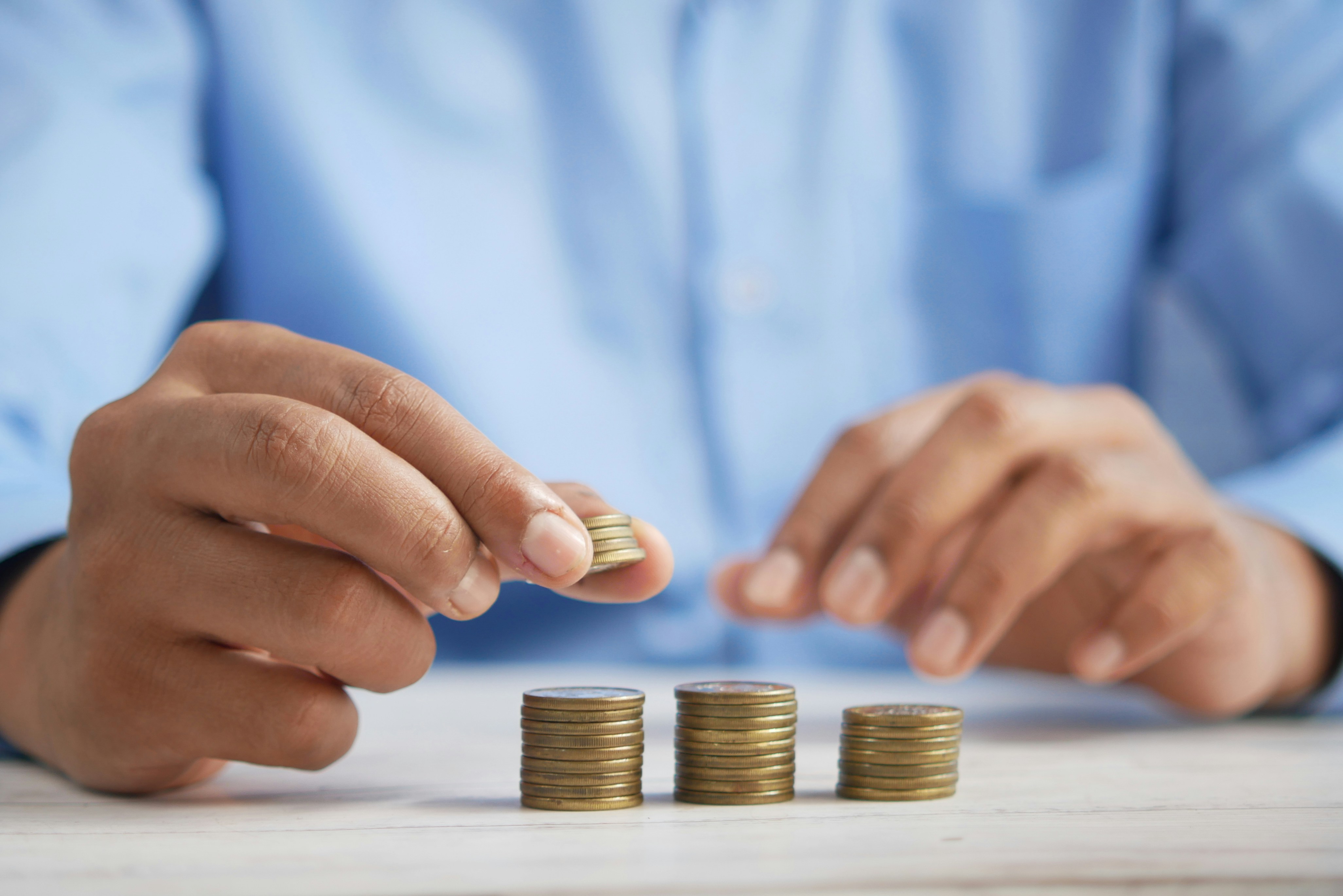 Photo of a hand holding change over straight piles of coins Photo of a hand holding change over straight piles of coins