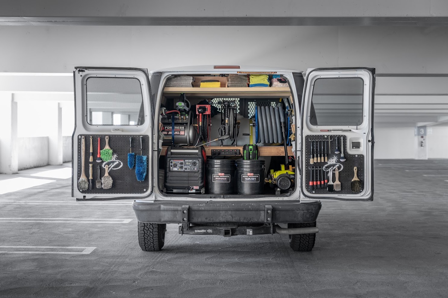 Opened back door of a van, revealing tools and gear.