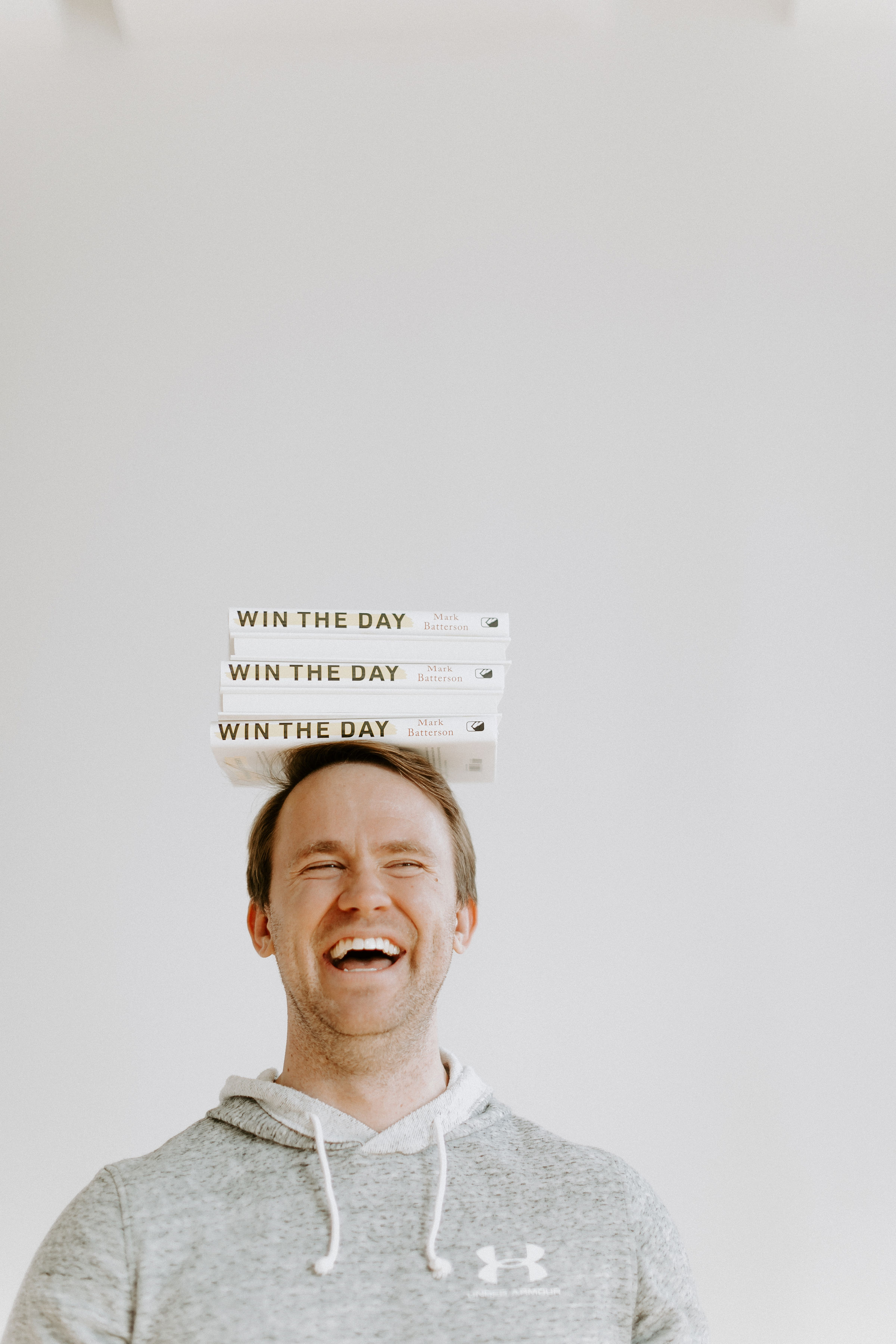 Man Smiling with a stack of books on his head