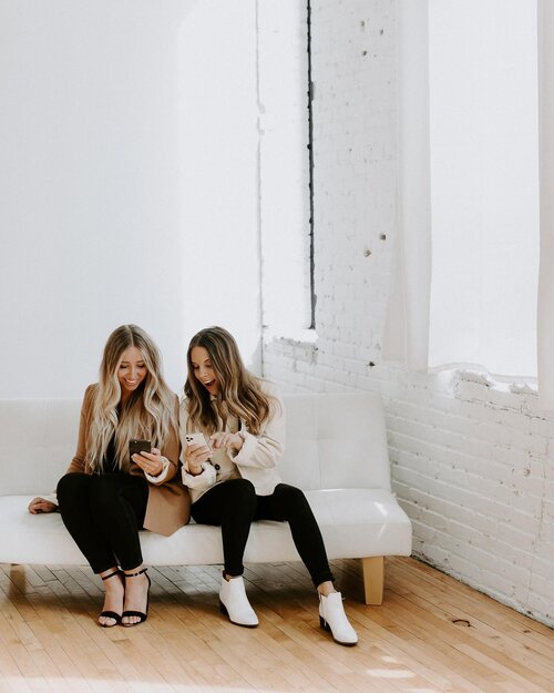 two girls looking at their phones and laughing