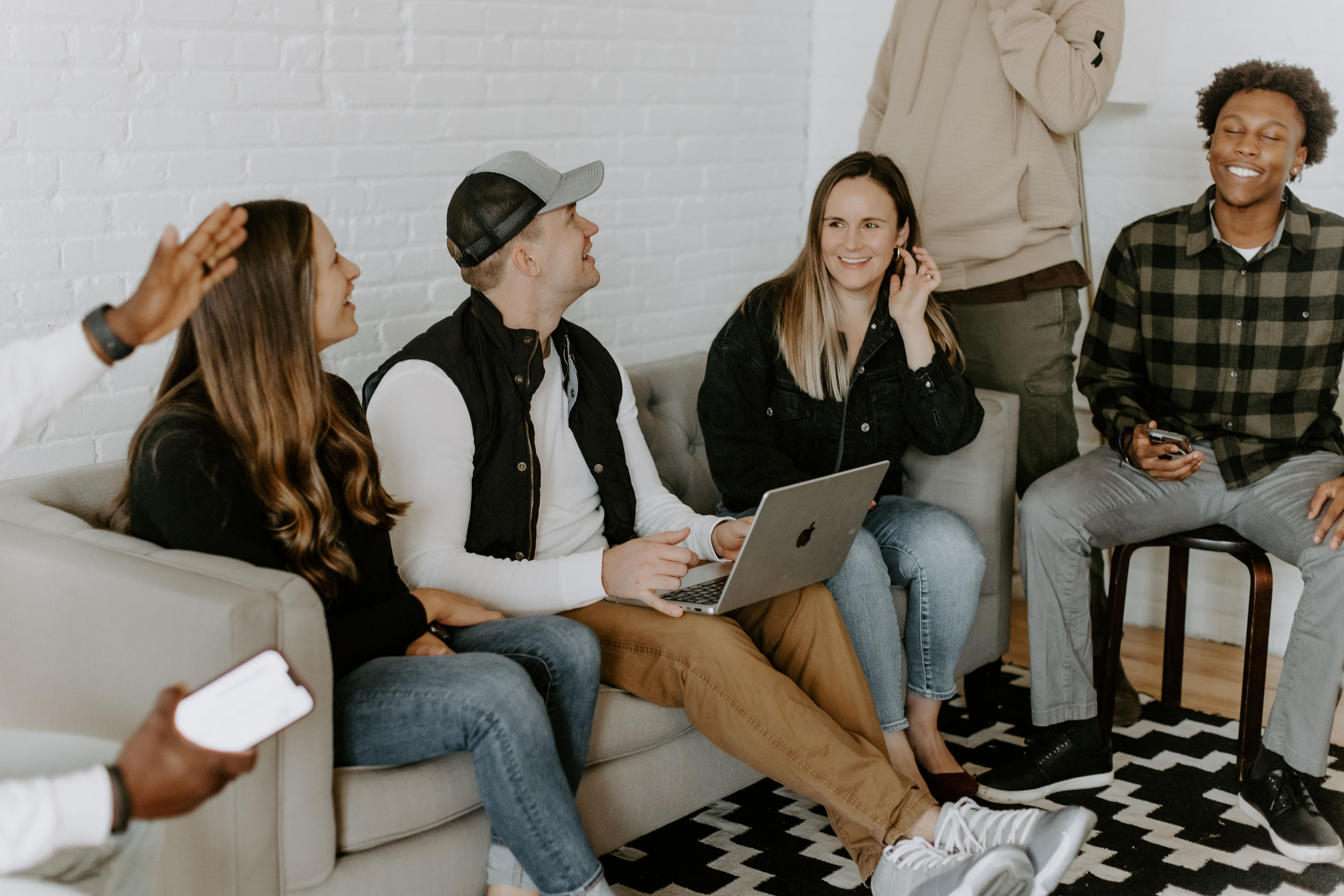 Team of people siting on a couch, talking, and smiling