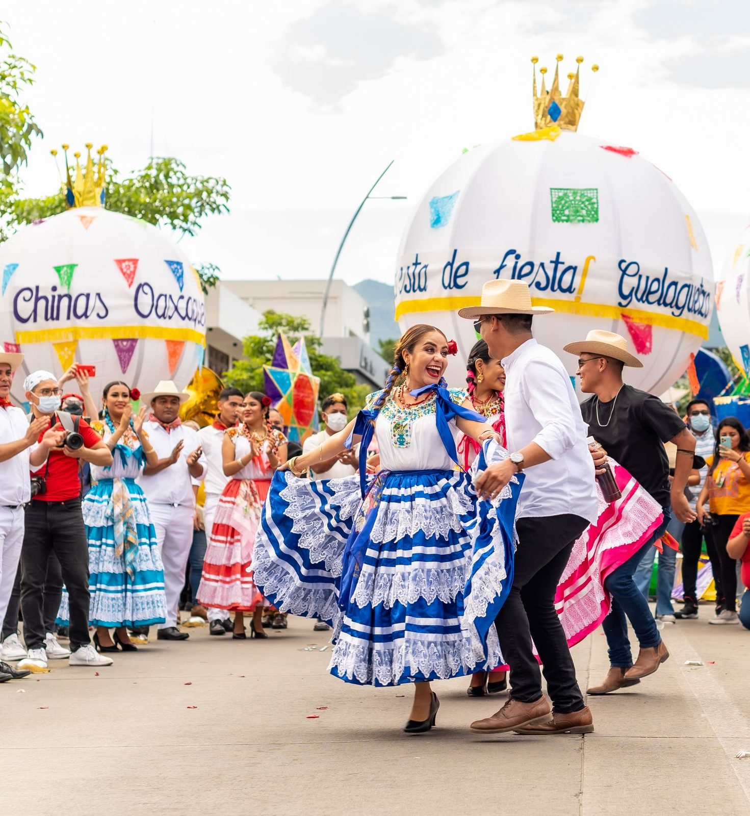 Dancers in traditional dress and a giant festival figure parading during the Guelaguetza in Oaxaca
