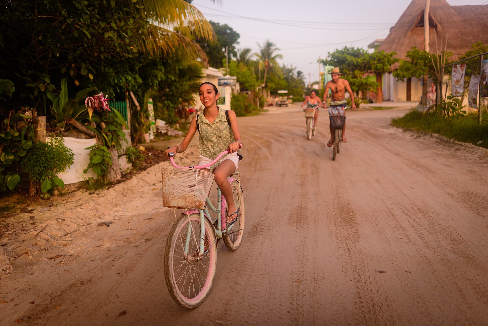 People riding bicycles down a sandy street on Isla Holbox