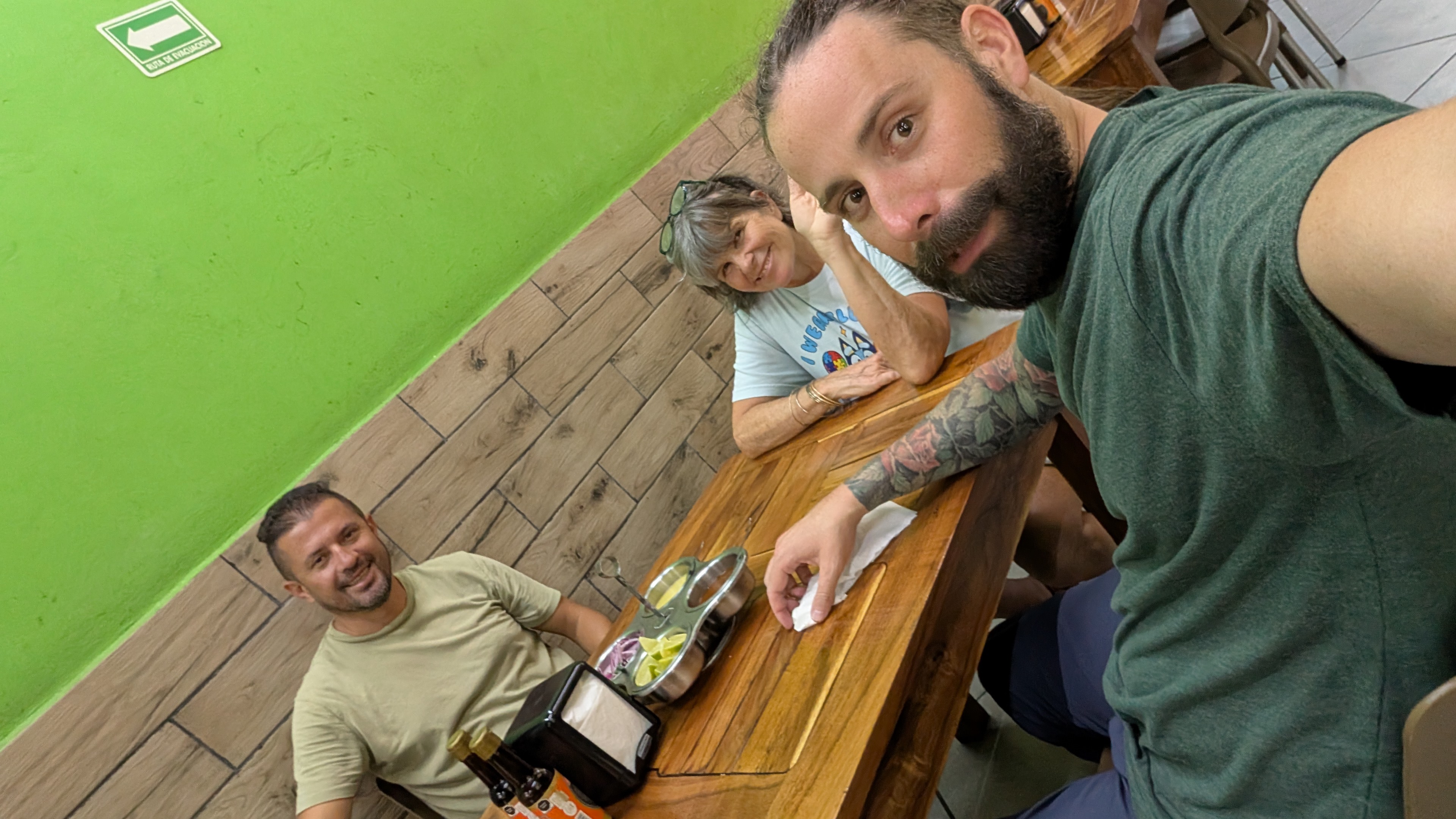 three people sitting at a table with al pastor tacos in valladolid mexico three people sitting at a table with al pastor tacos in valladolid mexico