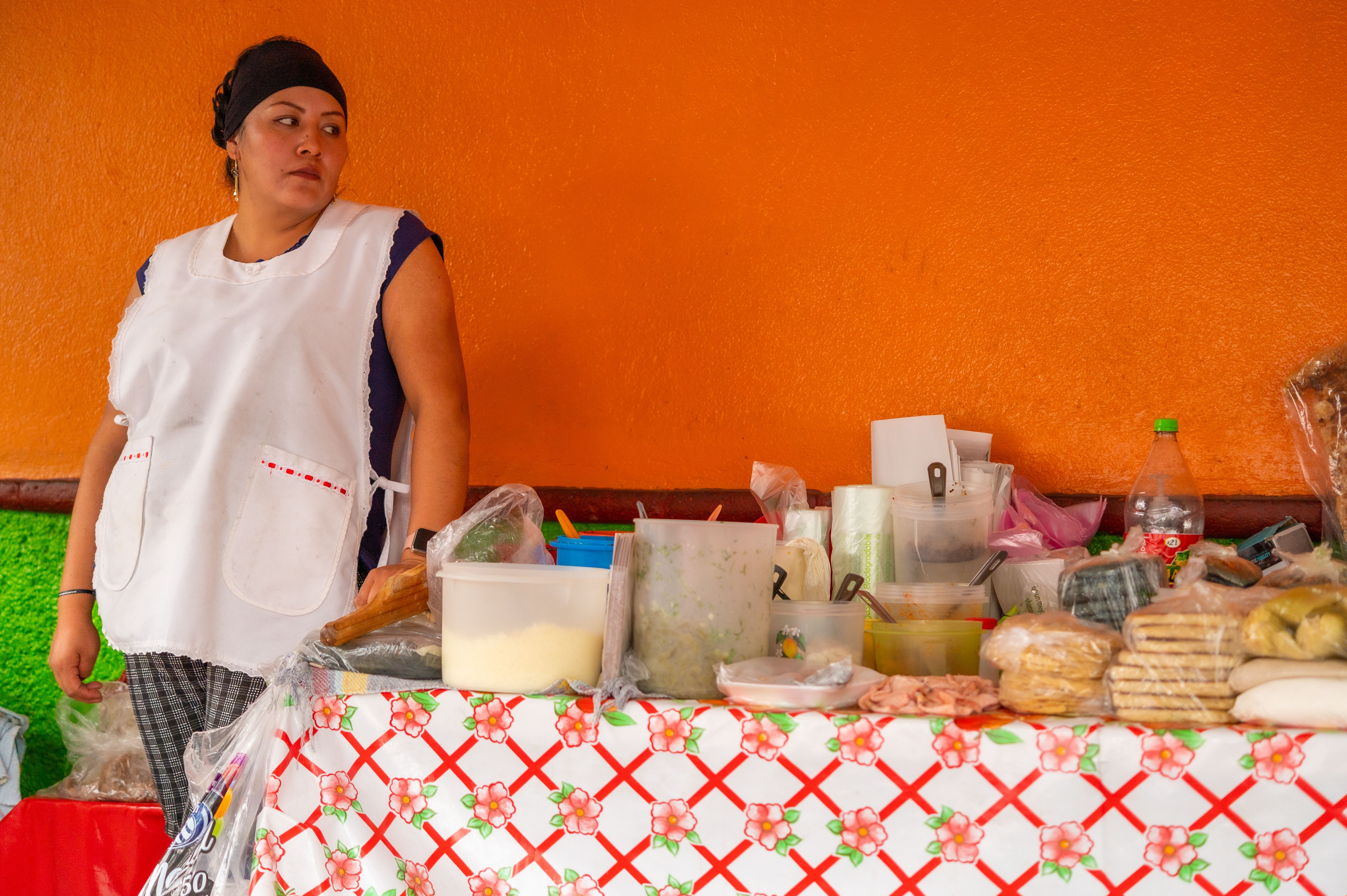 A market food stall assembling panuchos and cochinita pibil tacos with banana leaves and pickled red onion A market food stall assembling panuchos and cochinita pibil tacos with banana leaves and pickled red onion
