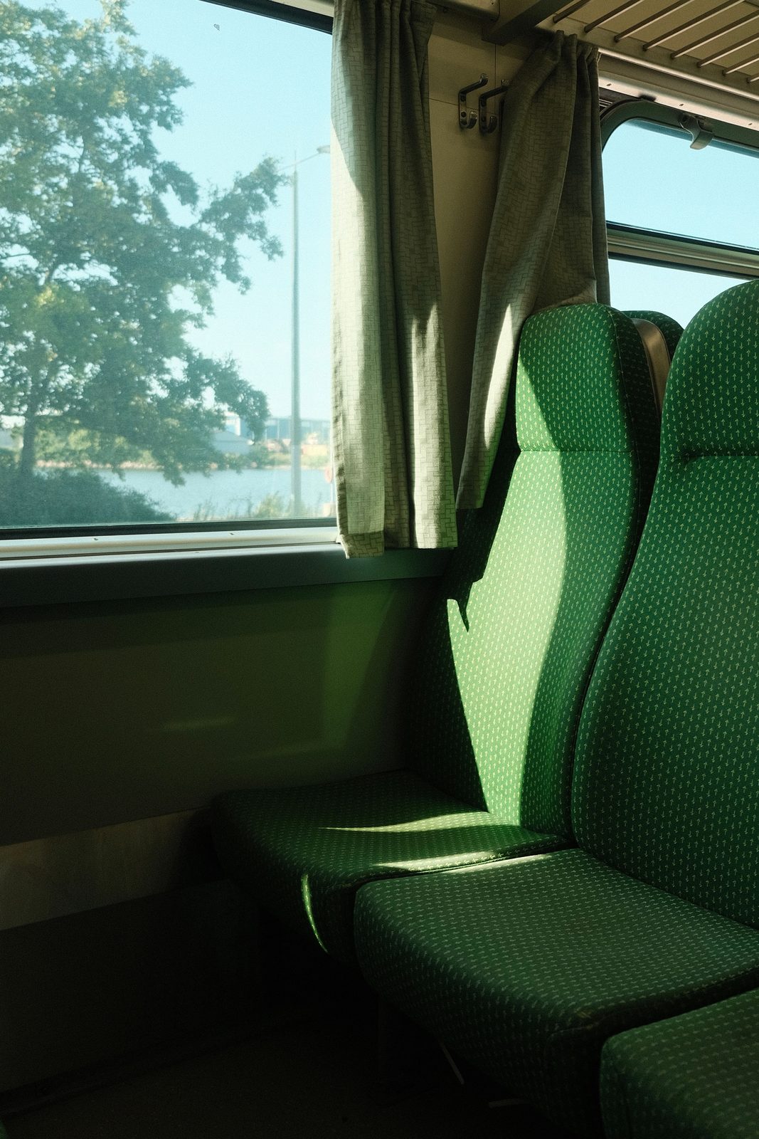 The interior of a train carriage with rows of forward-facing seats and large panoramic windows