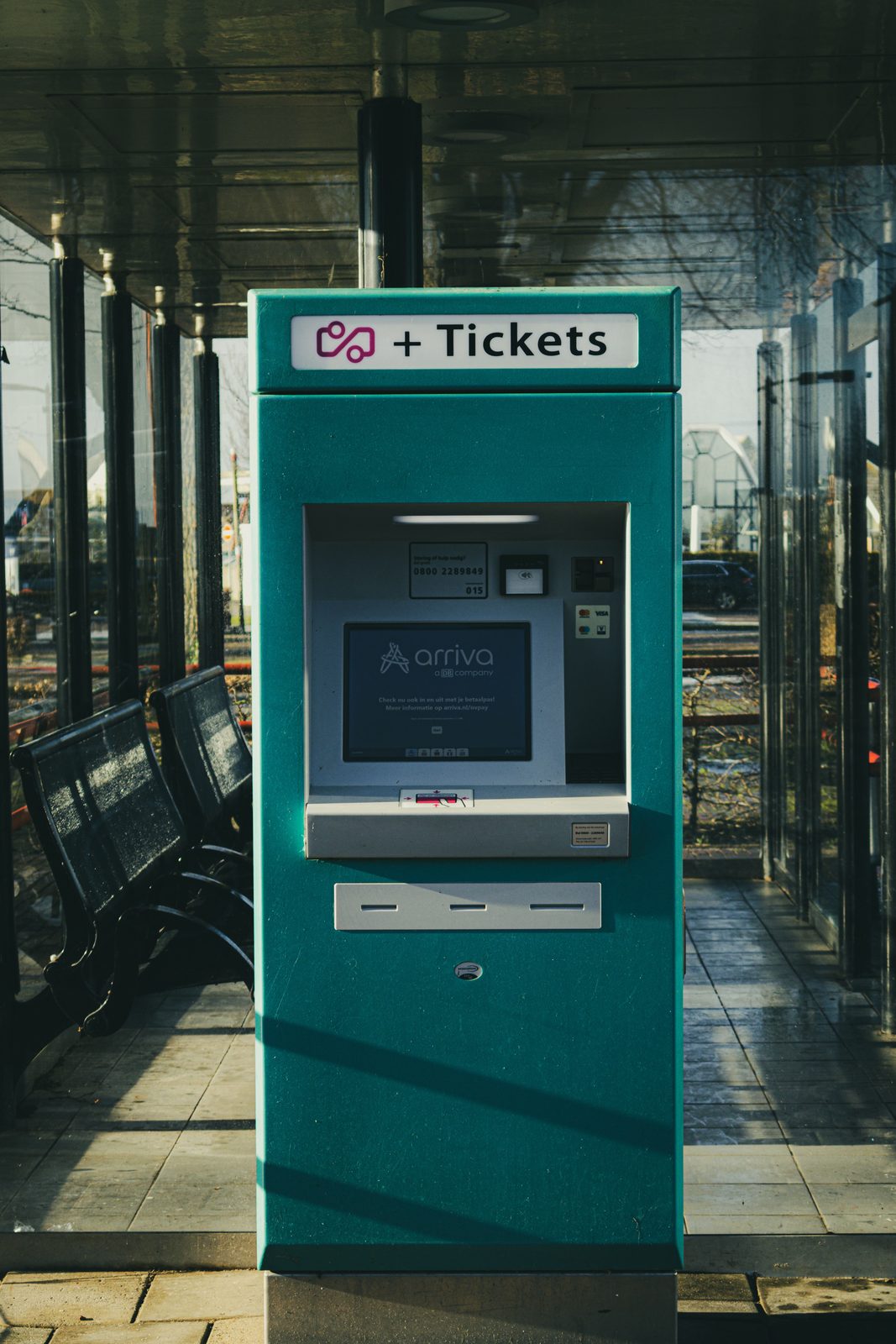 A close-up of a train ticket kiosk screen at a station with a passenger using it