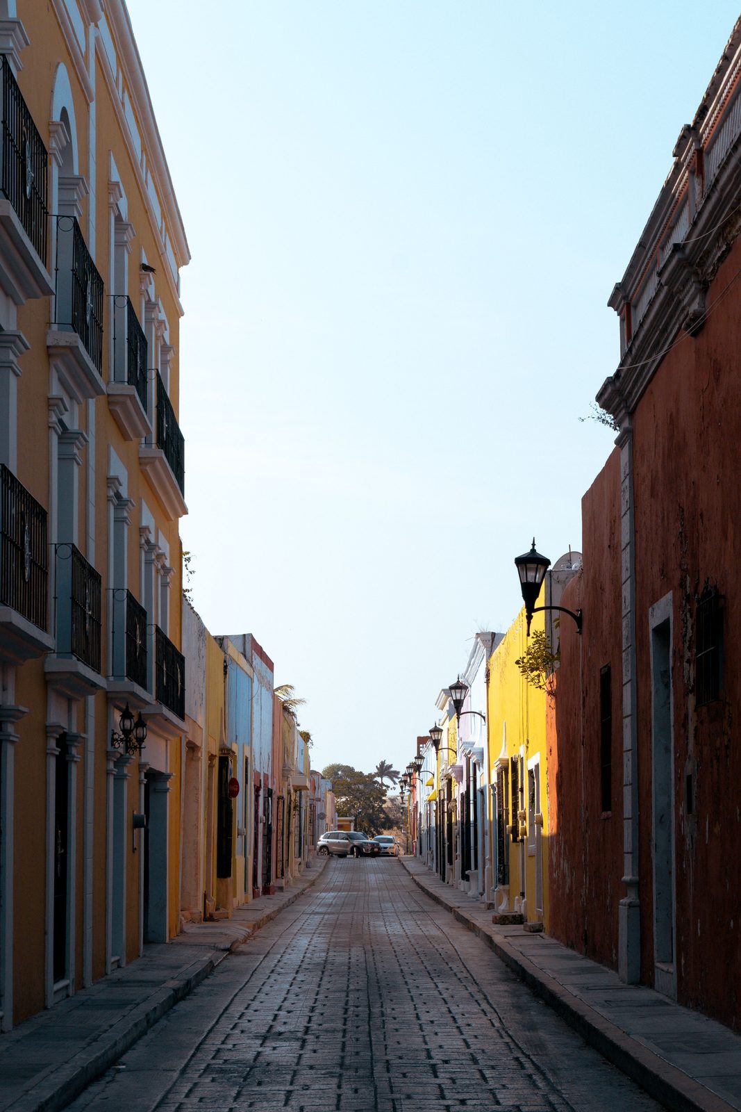 A pastel sea-wall street in Campeche's historic center, colonial facades in yellow, blue, and coral, empty in the early morning light.
