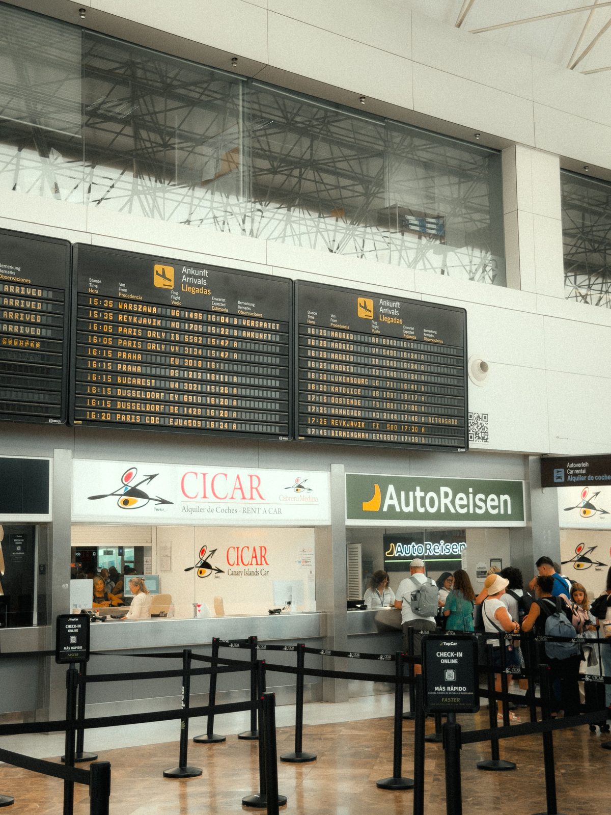 A row of car rental counters inside a Cancún airport terminal, branded signage for the major international rental companies, a line of travelers waiting A row of car rental counters inside a Cancún airport terminal, branded signage for the major international rental companies, a line of travelers waiting