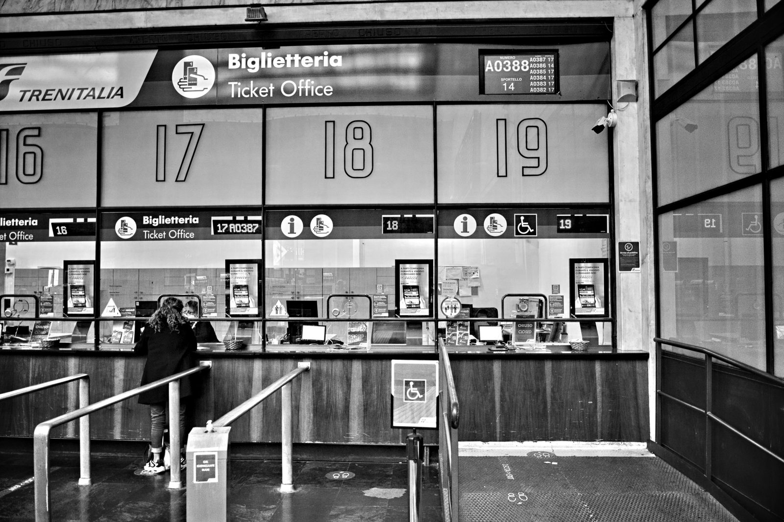 Inside an ADO bus terminal counter at Cancún airport, a passenger buying a ticket at a self-service kiosk with a departures board overhead Inside an ADO bus terminal counter at Cancún airport, a passenger buying a ticket at a self-service kiosk with a departures board overhead