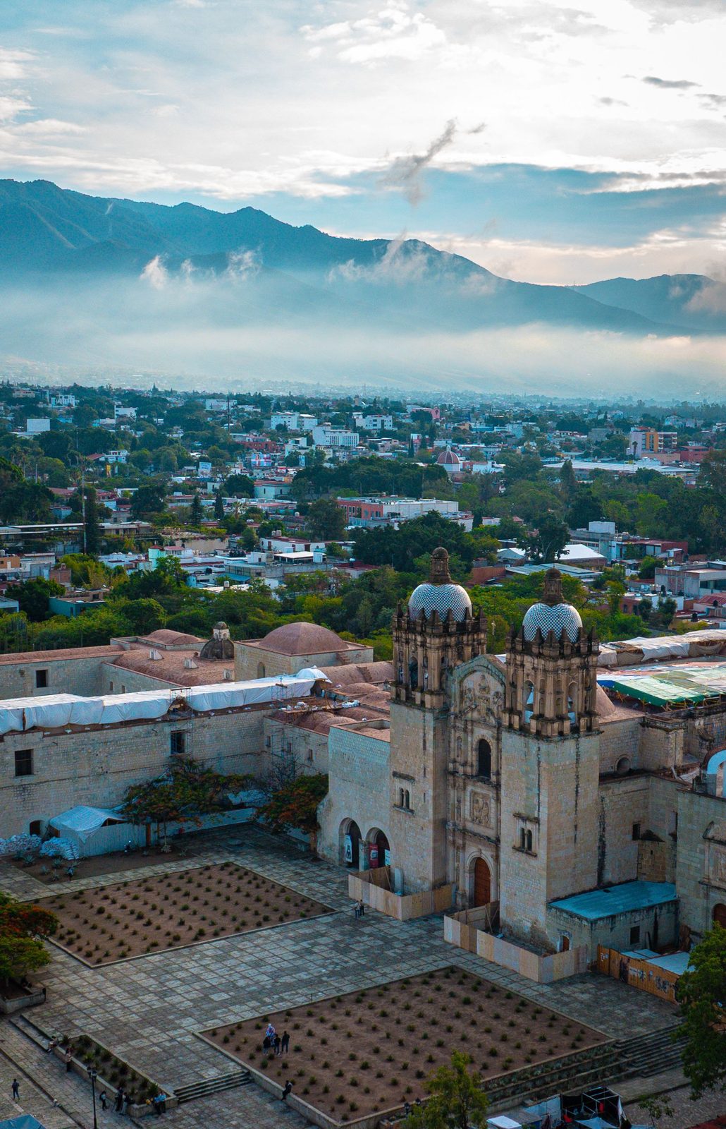 Aerial view of the Templo de Santo Domingo de Guzm&aacute;n and Oaxaca City's historic center, with the surrounding rooftops and mountains beyond