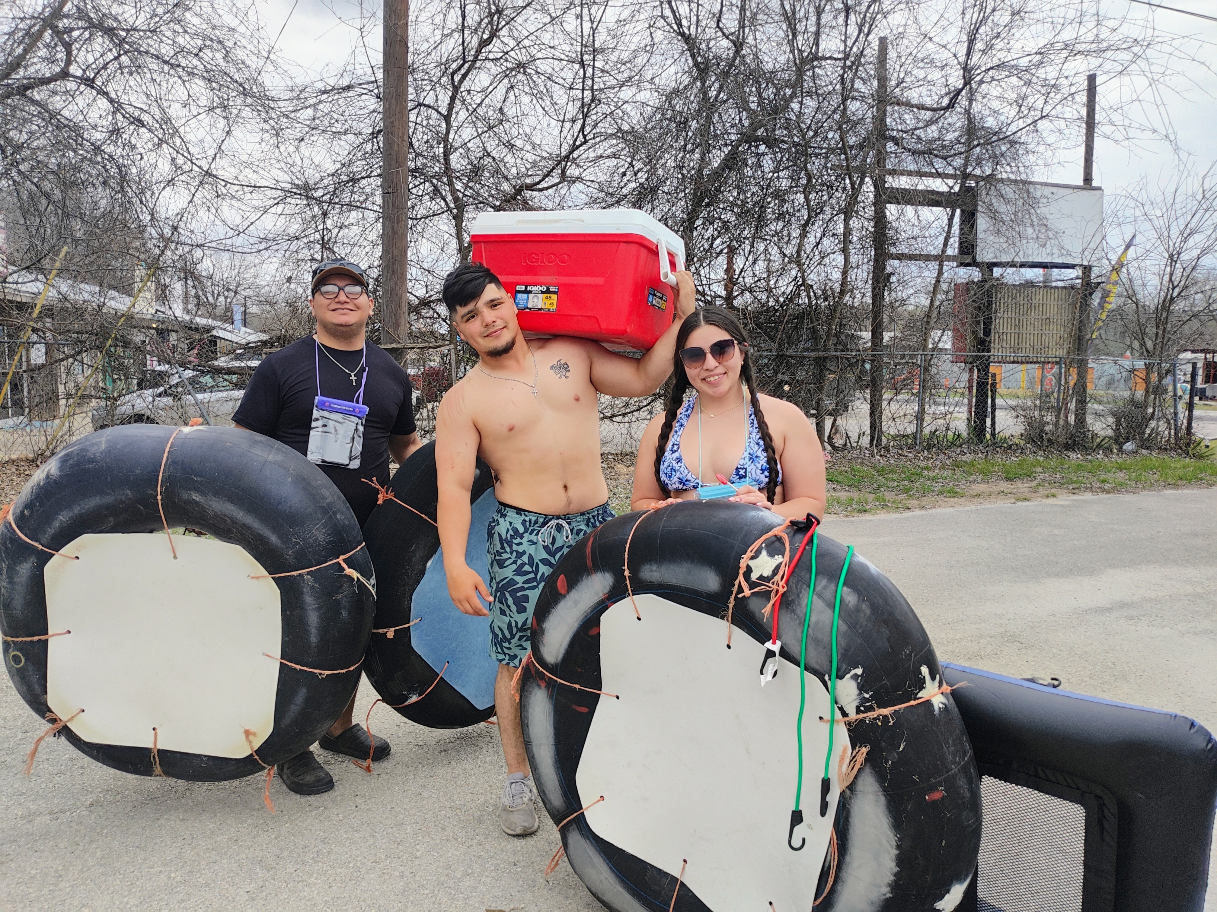 Group of friends carrying river tubes and a cooler before floating with Tube Haus in Canyon Lake, Texas.