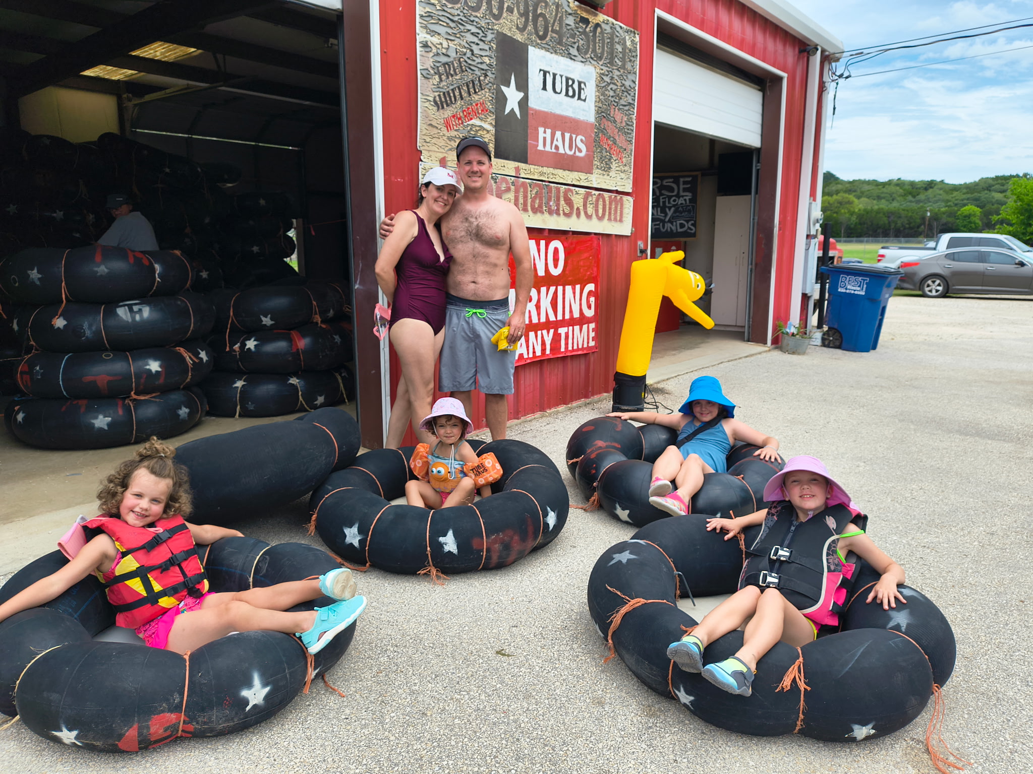 Family preparing for a fun river tubing adventure at Tube Haus near Canyon Lake, Texas with tubes, life jackets, and children ready to float.