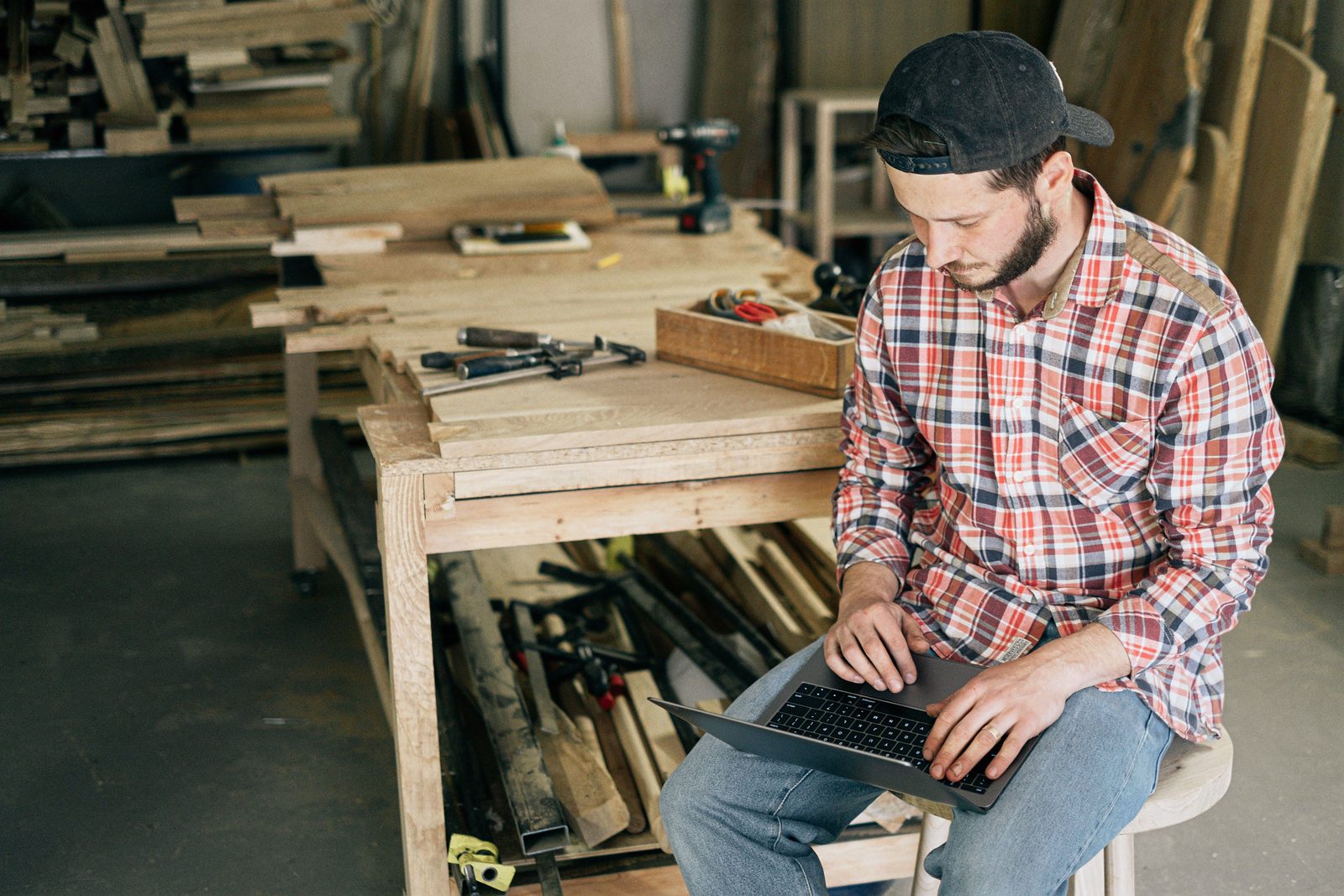 A small business owner working on a laptop in his woodworking shop