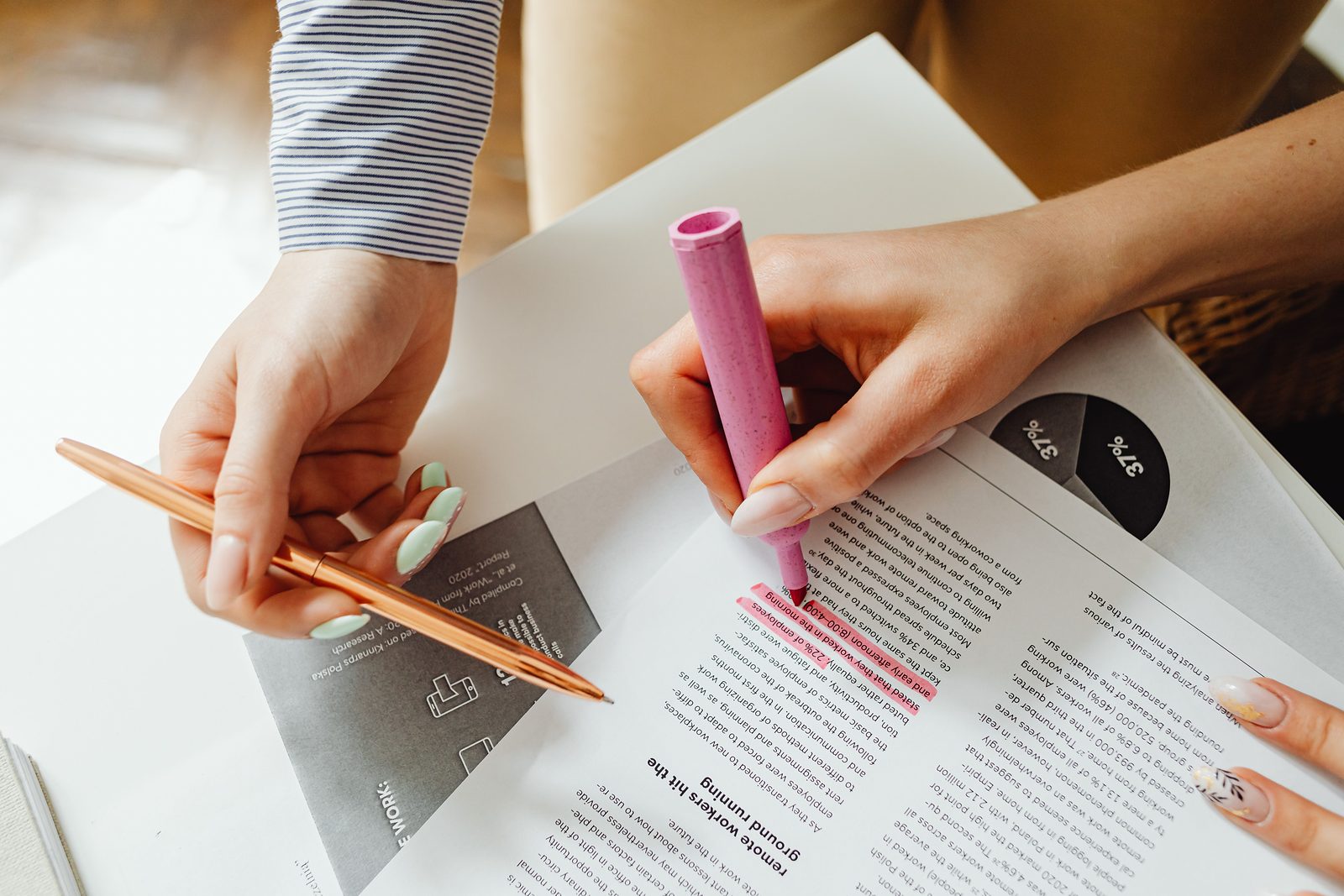 Hands marking key lines of a printed document with a highlighter and pen