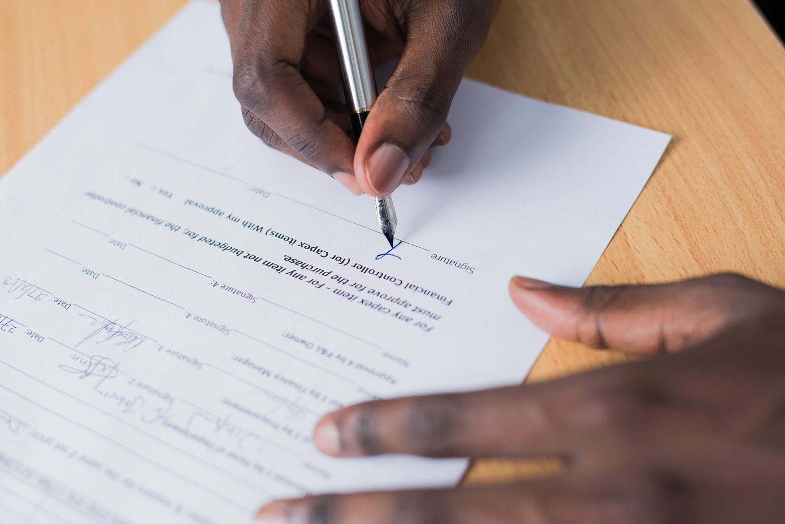 A hand signing a printed agreement with a pen