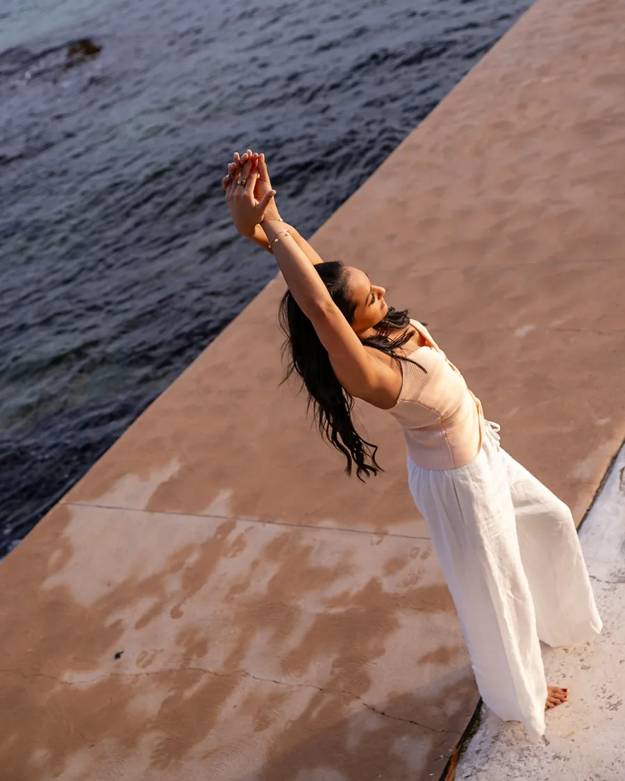 Saddy by the water, her arms raised and her face to the sky
