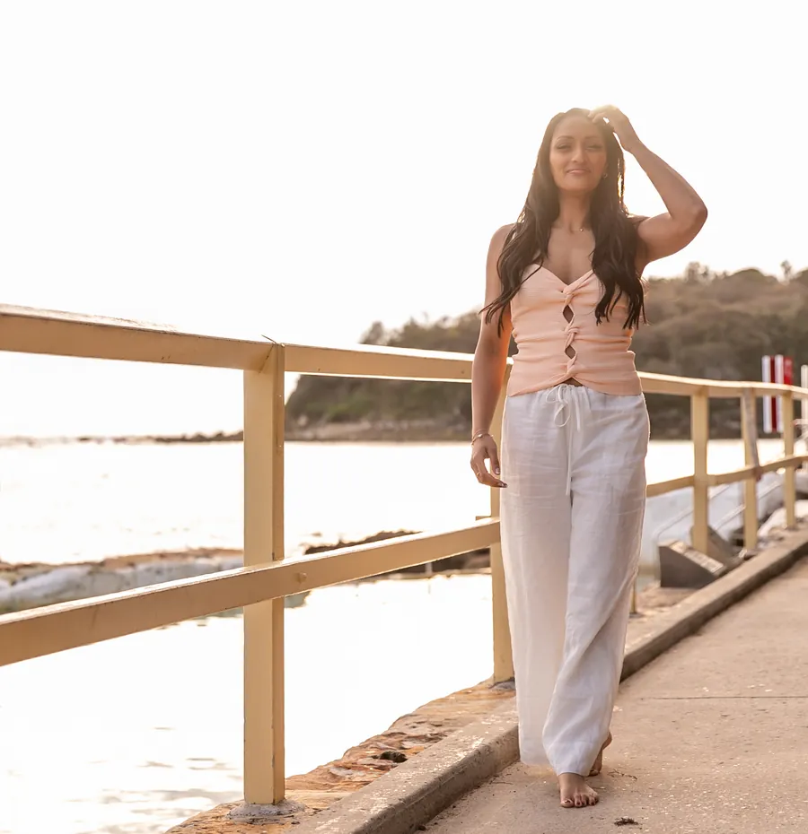 Saddy walking along the jetty towards the camera, smiling, one hand in her hair