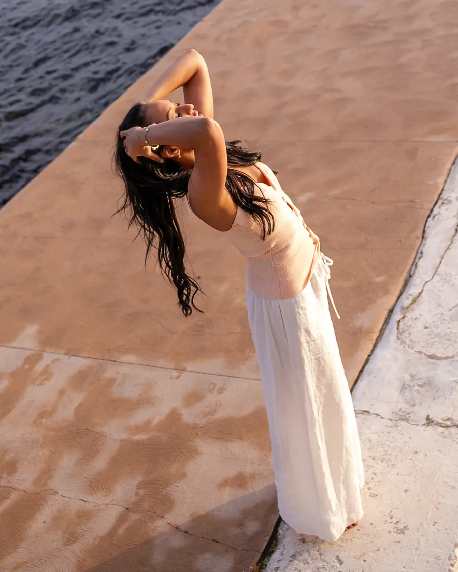 Saddy leaning back by the water, eyes closed, her hands in her hair