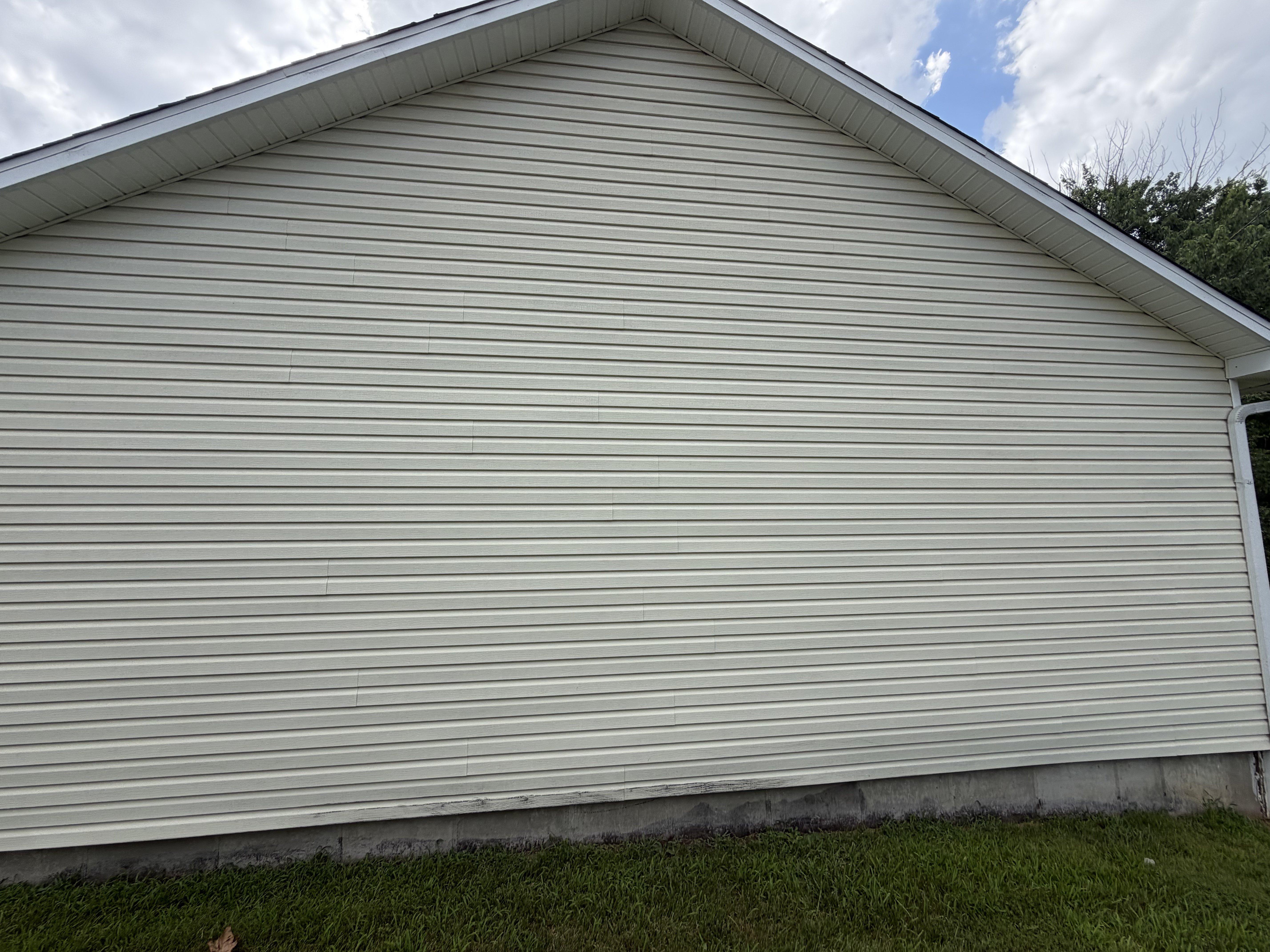 A home roofline and siding under a bright sky.