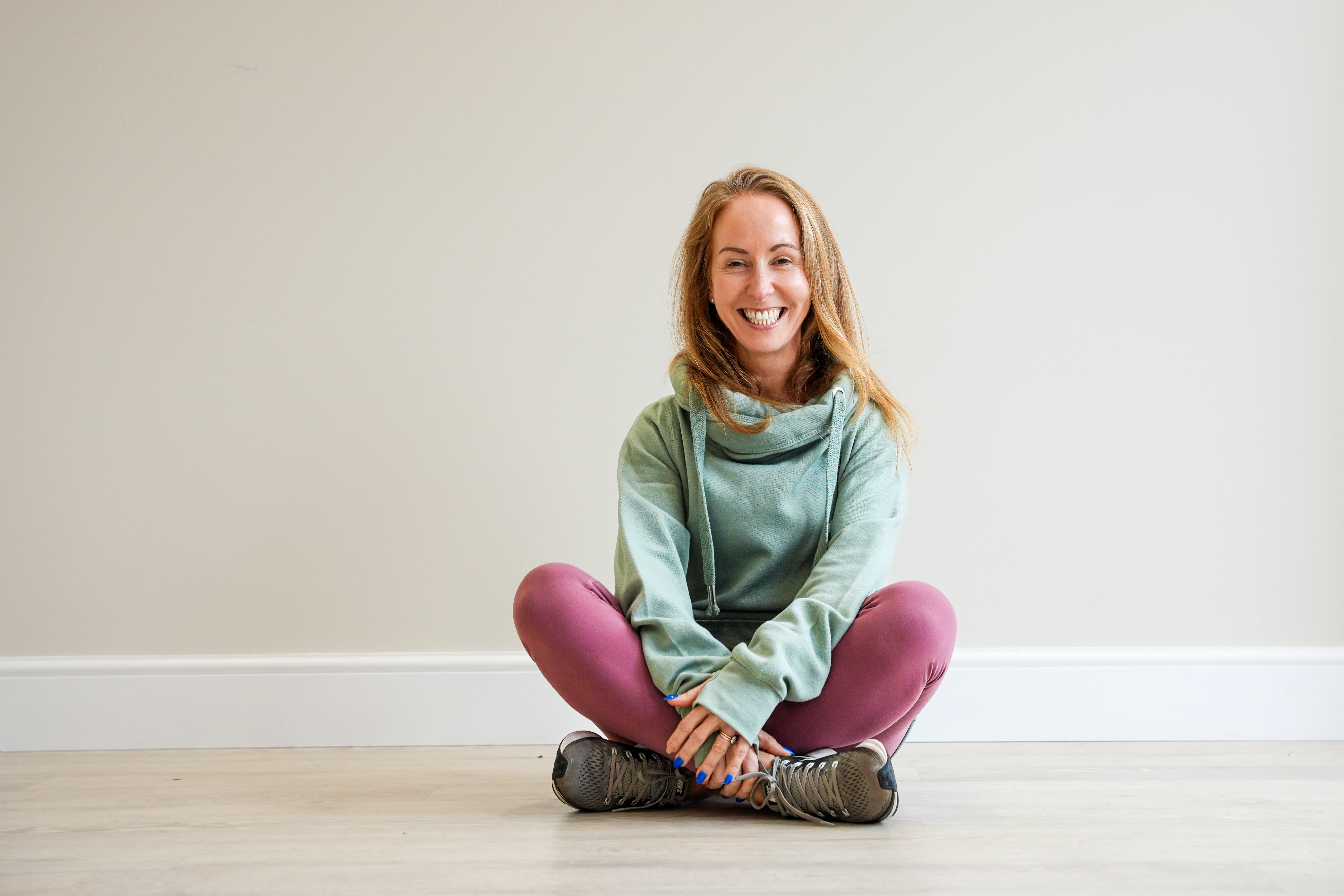 Suzanne Haynes, founder of Belle Vitale Wellness, sitting cross-legged in the studio