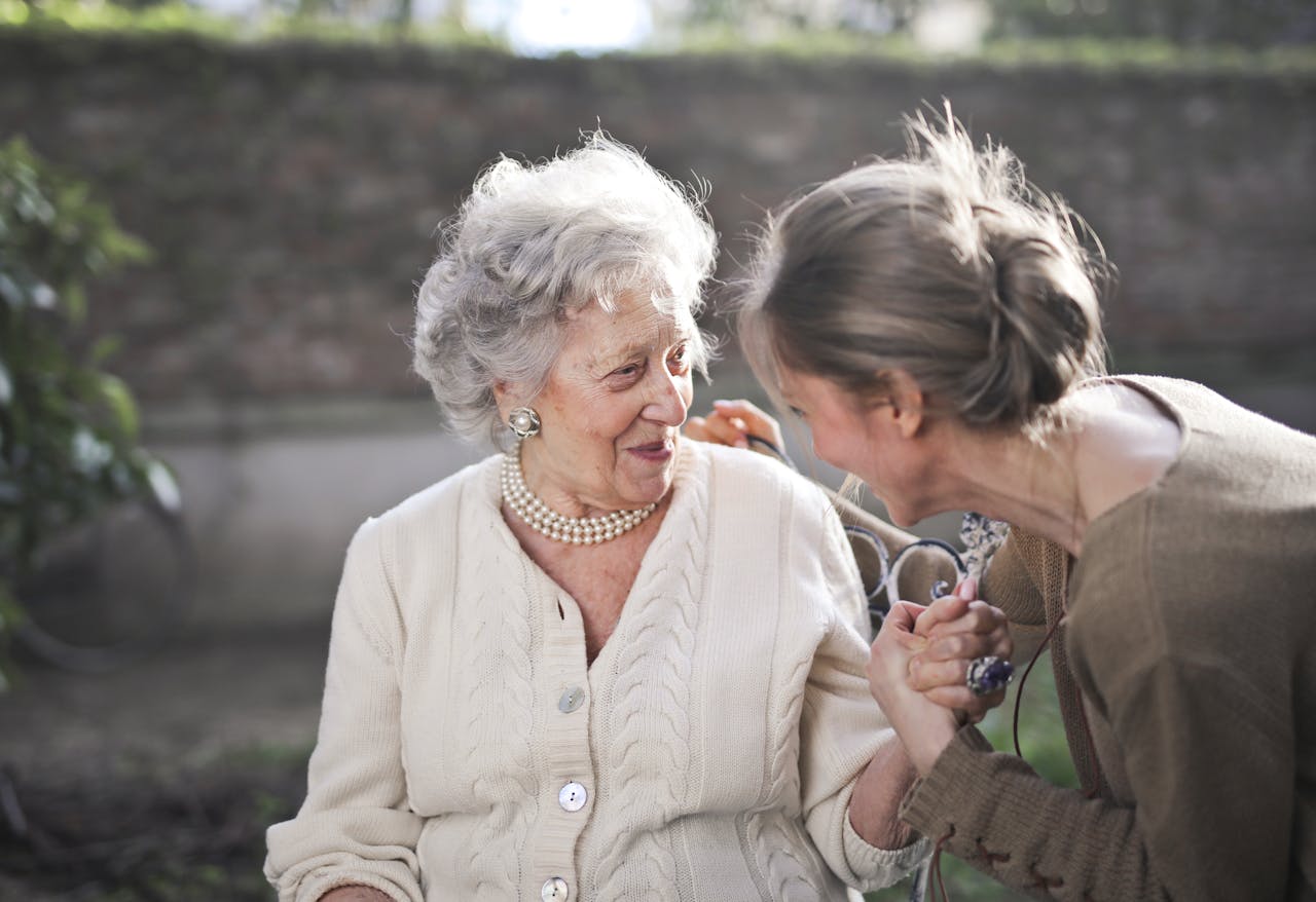 The Elderly woman chatting happily with a caregiver outdoors, showcasing compassionate care by Medical Insurance Advisory.