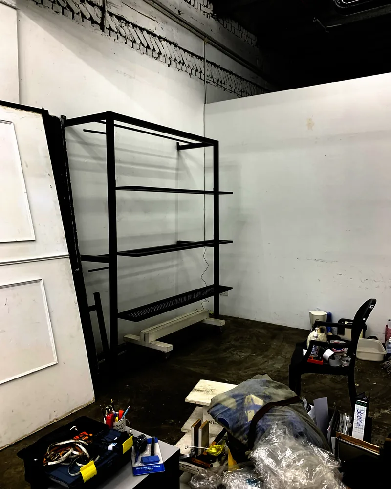 Empty white studio room mid build-out with shelving and equipment racks going in