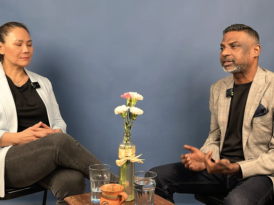 Two person interview being filmed against a blue backdrop in the studio