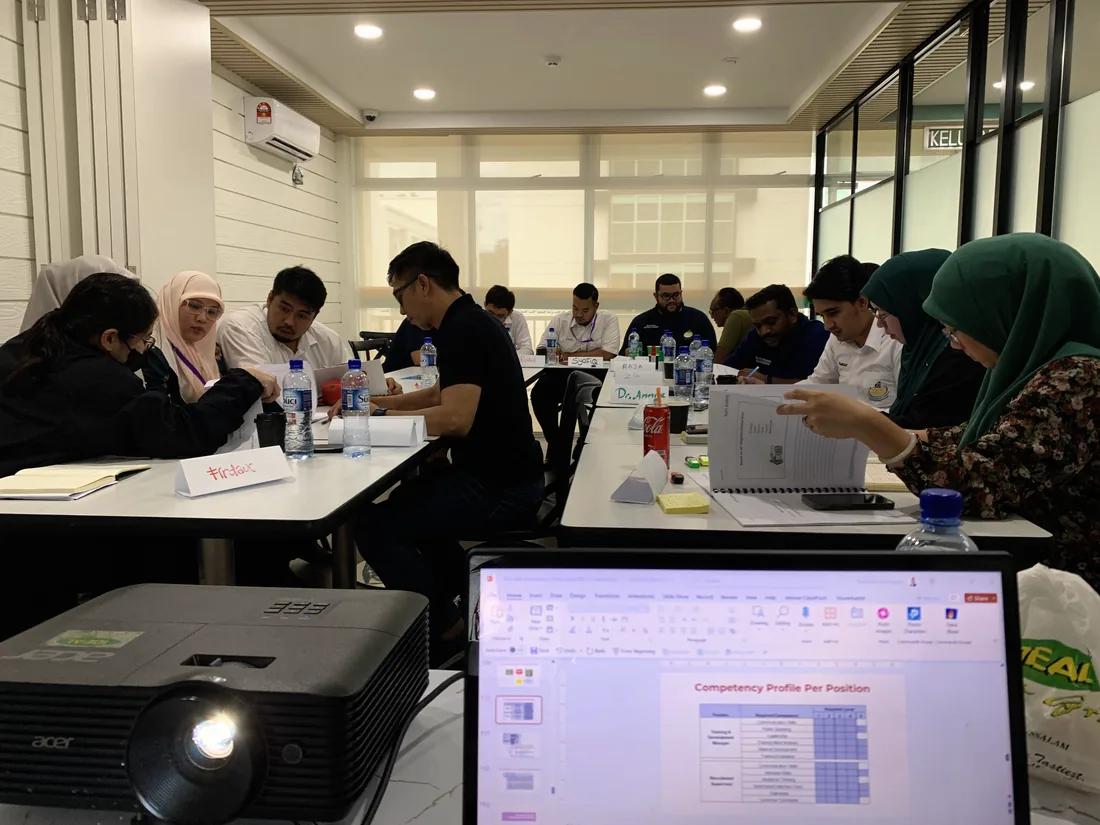 Wide view of a corporate training room mid session with participants seated