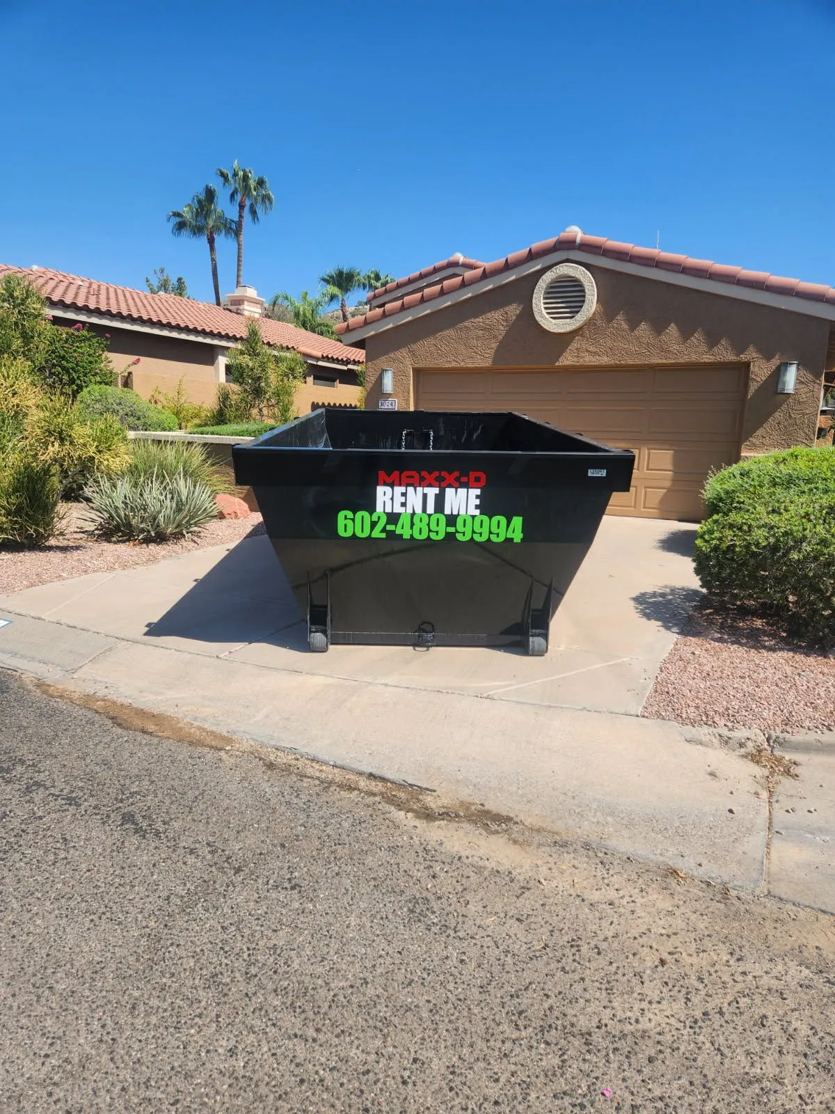 Black MAXX-D rental container marked RENT ME in a residential driveway.