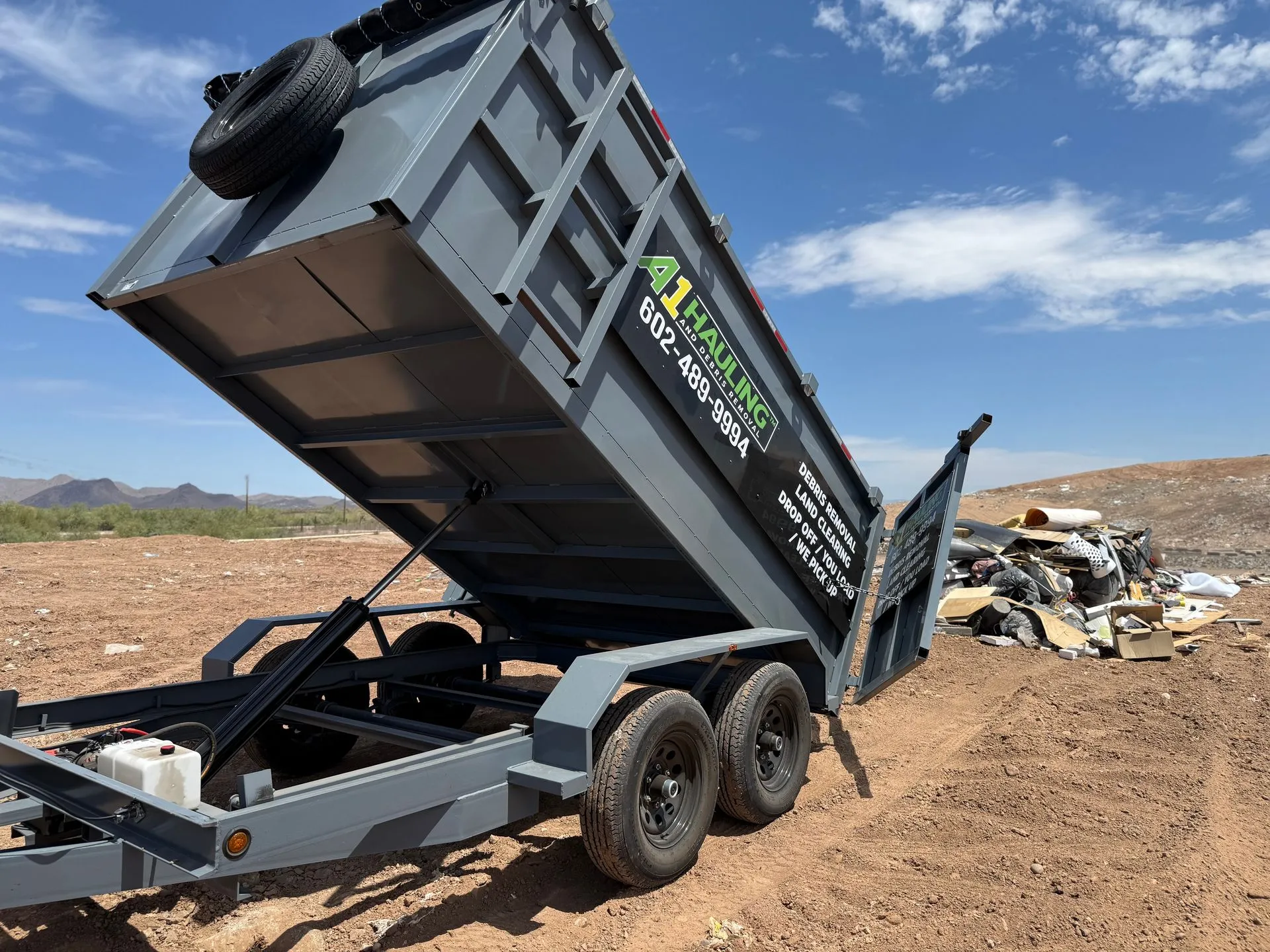 A1-branded dump trailer raised at a disposal site, unloading material.