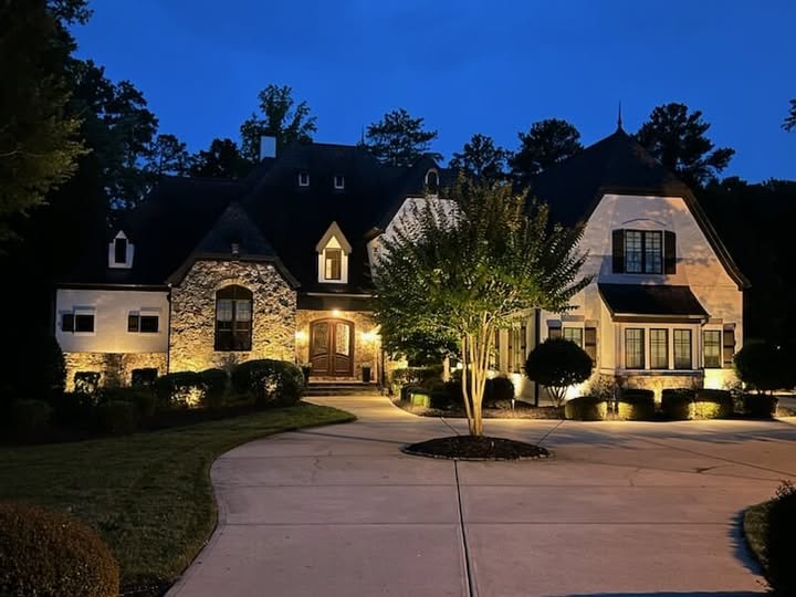 Stone and stucco home in Rock Hill with façade uplighting and a lit crape myrtle