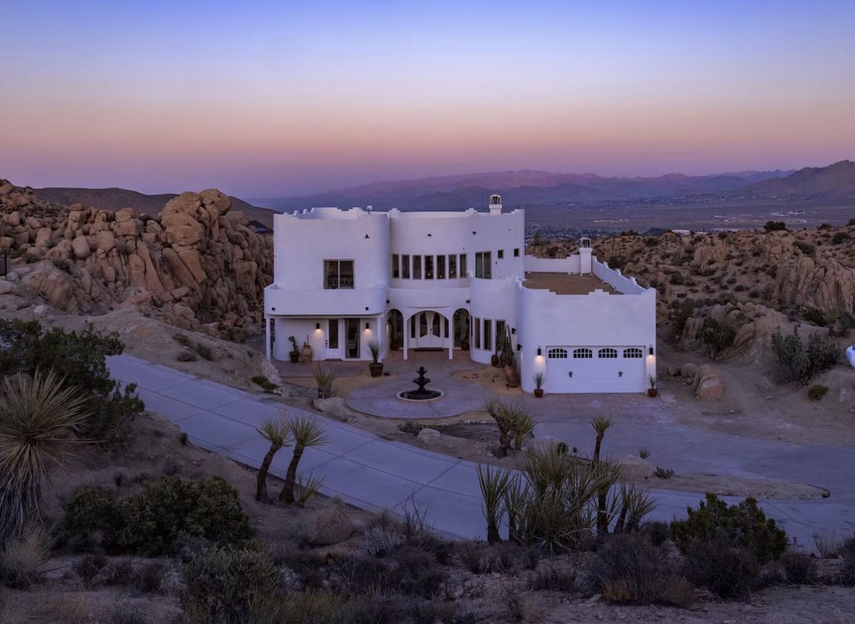 White adobe retreat house among Joshua Tree boulders at dusk