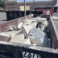 A cleared San Antonio demolition site with concrete rubble and broken masonry loaded into a haul truck by a debris removal crew. The surrounding lot is swept clean and ready for the next phase of construction.