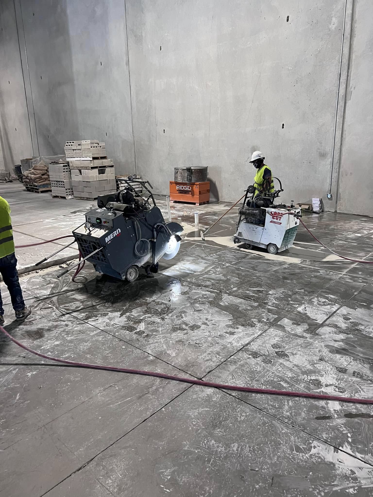 A concrete contractor operating a flat-blade saw to cut a straight trench line through an interior concrete slab in a San Antonio residential home. The cut edges are clean and the surrounding floor remains undisturbed.