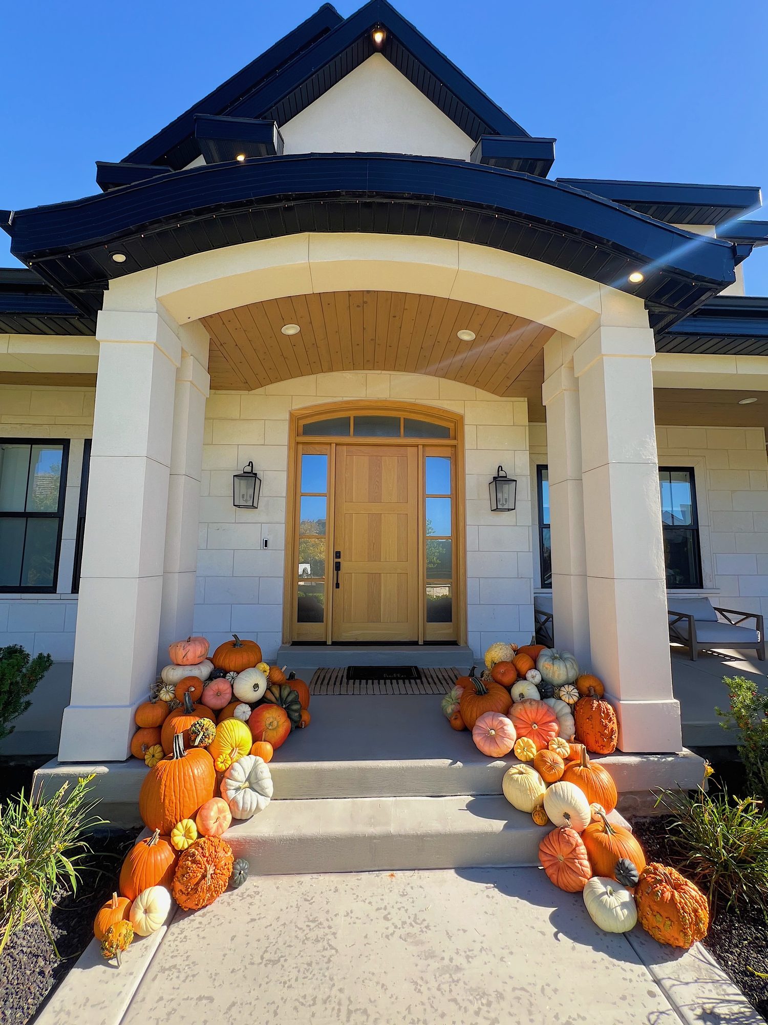Pumpkins and mums framing a white brick front porch