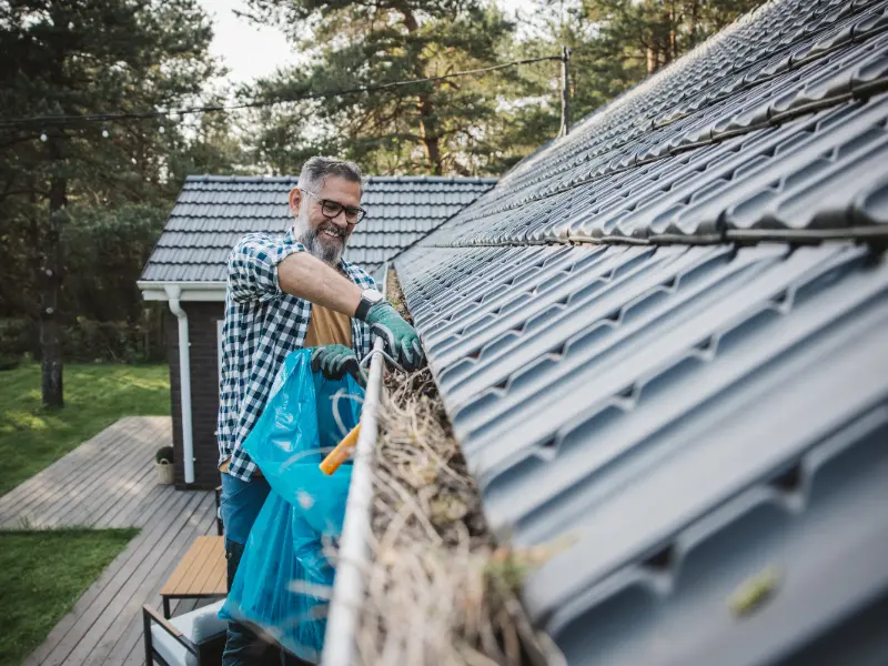 Homeowner bagging gutter debris during gutter cleaning.