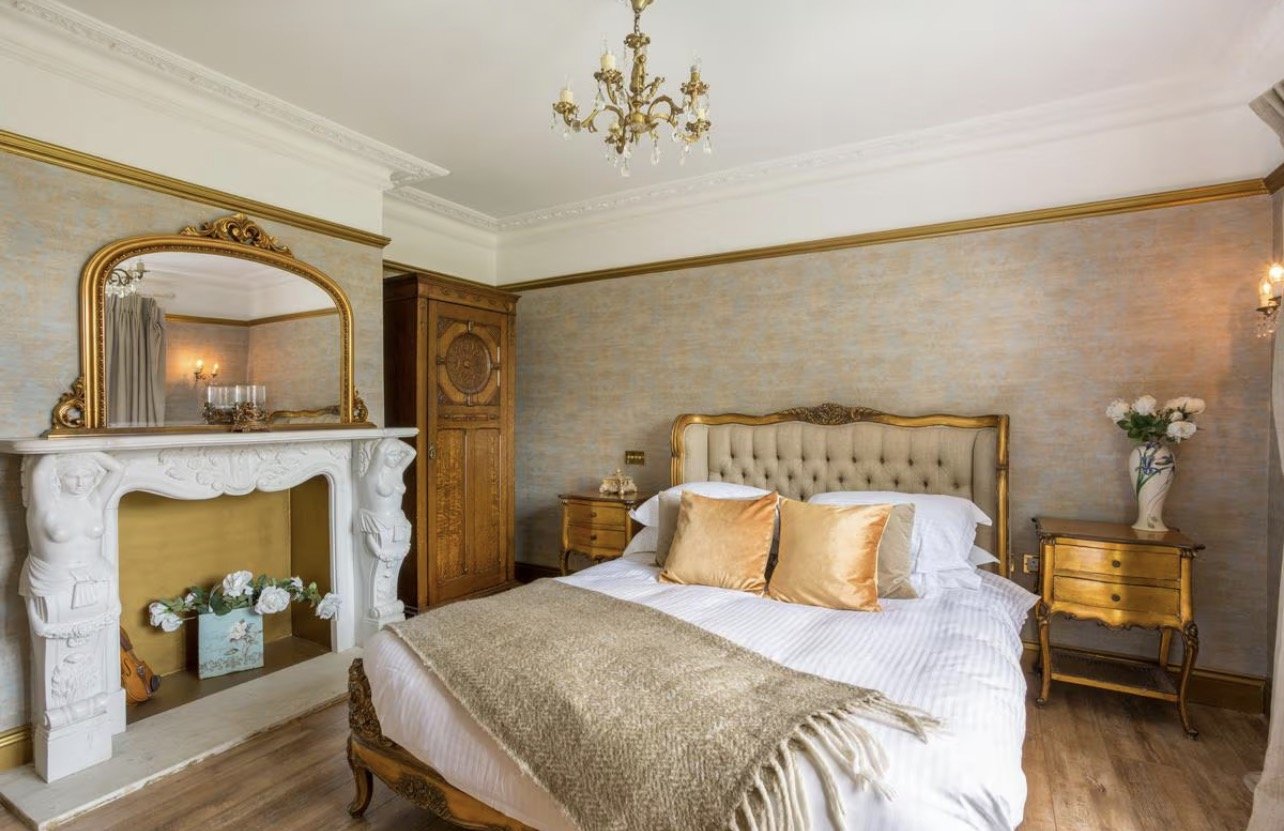 An elegant bedroom with gold accents and a fireplace