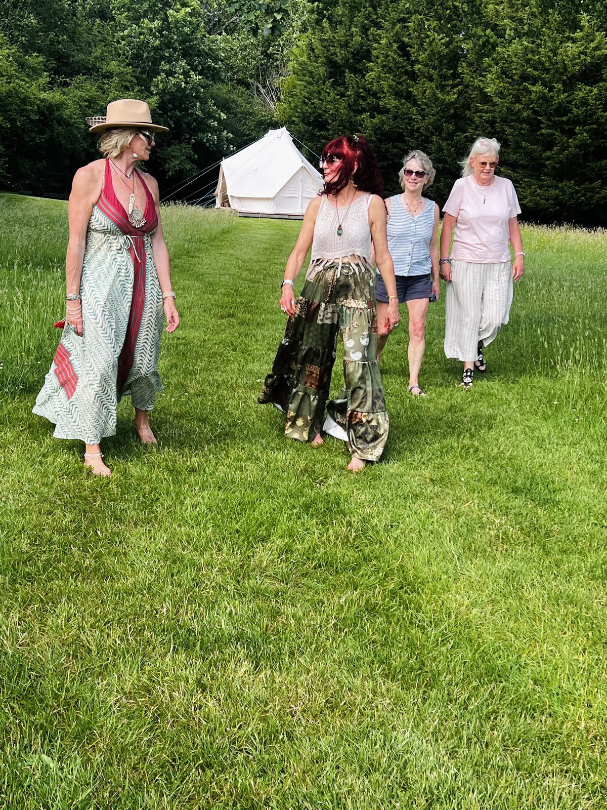 A group of women walking across the lawn, with a bell tent behind them