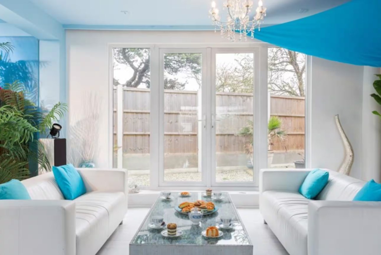 A bright lounge with white sofas, tropical plants and afternoon tea laid out