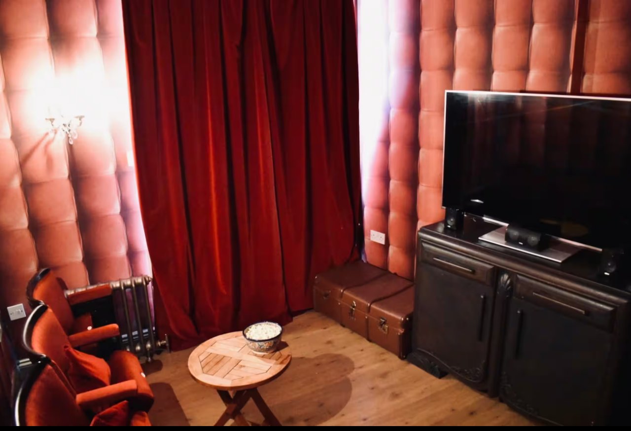 A cosy den with red velvet curtains and a television